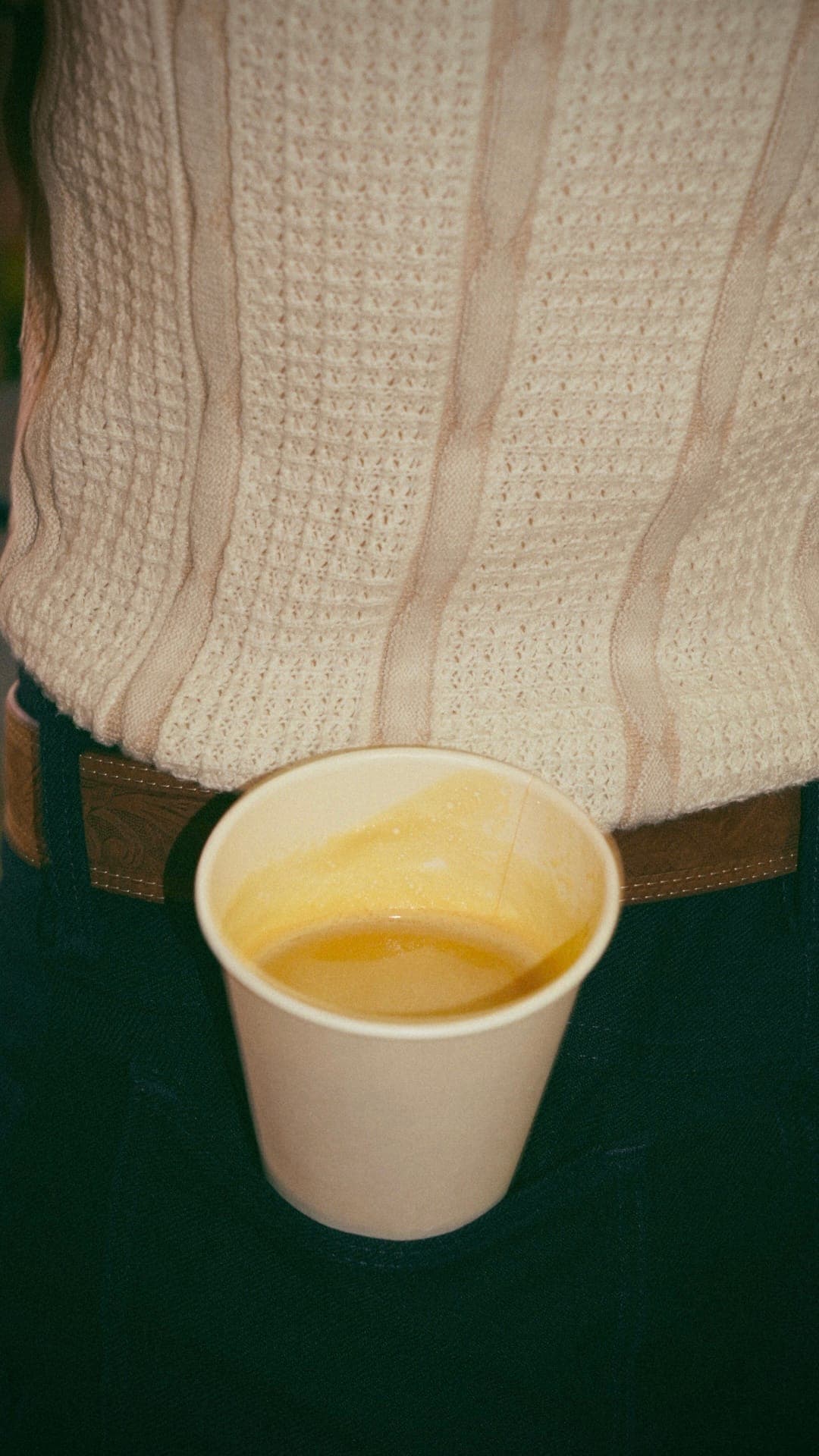Customer holding a latte in ceramic mug, warm cafe interior in background