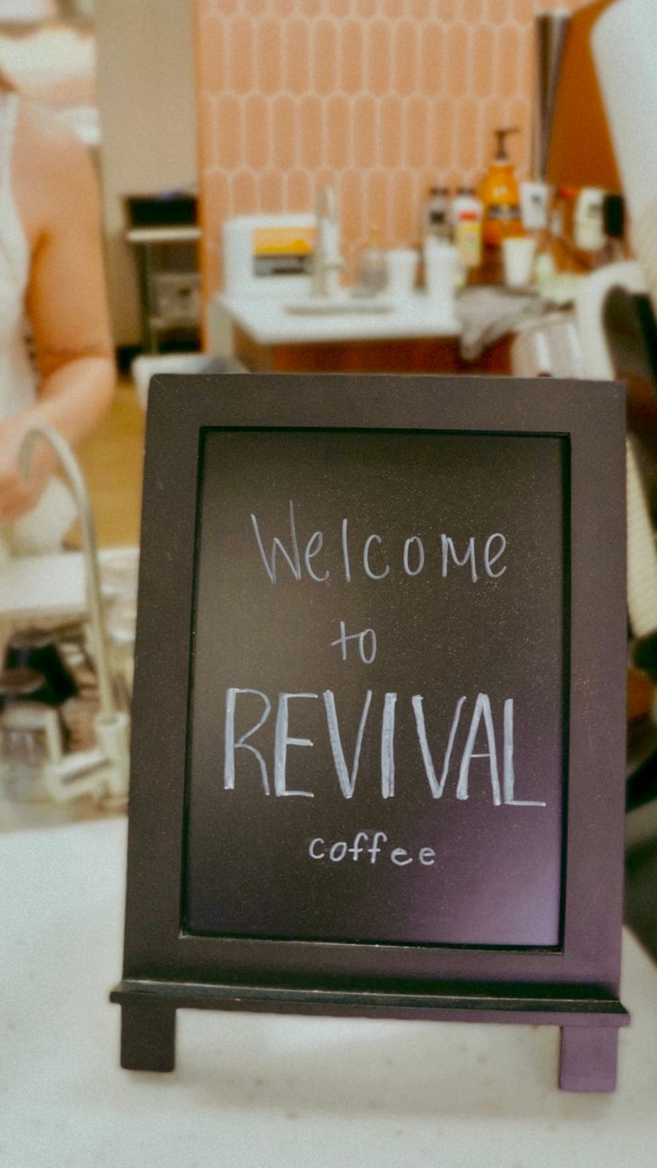 Warm wood welcome sign and cream tile entryway at an independent cafe